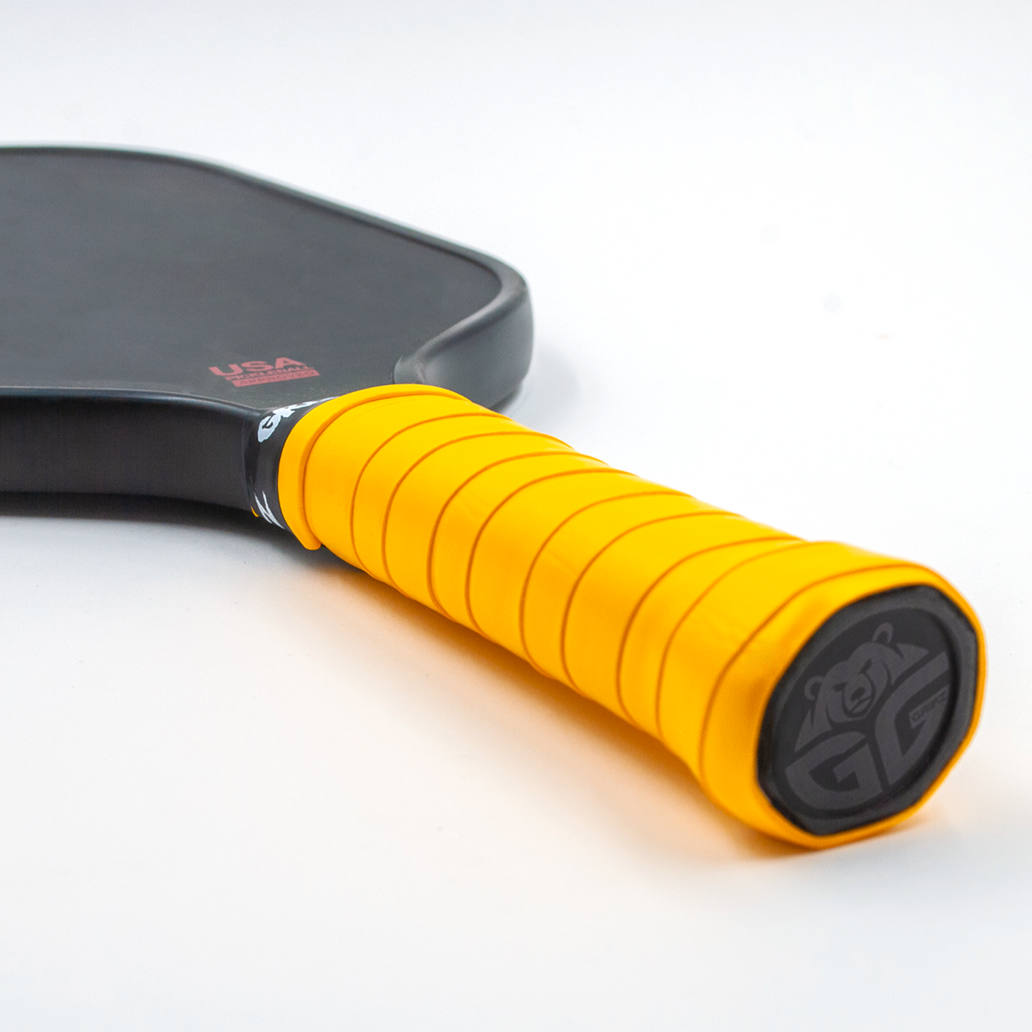 Neon Orange grizzlee Gripz wrapped around a paddle handle thats laying flat on a white surface - Premium Pickleball Overgrip by Grizzlee Gripz