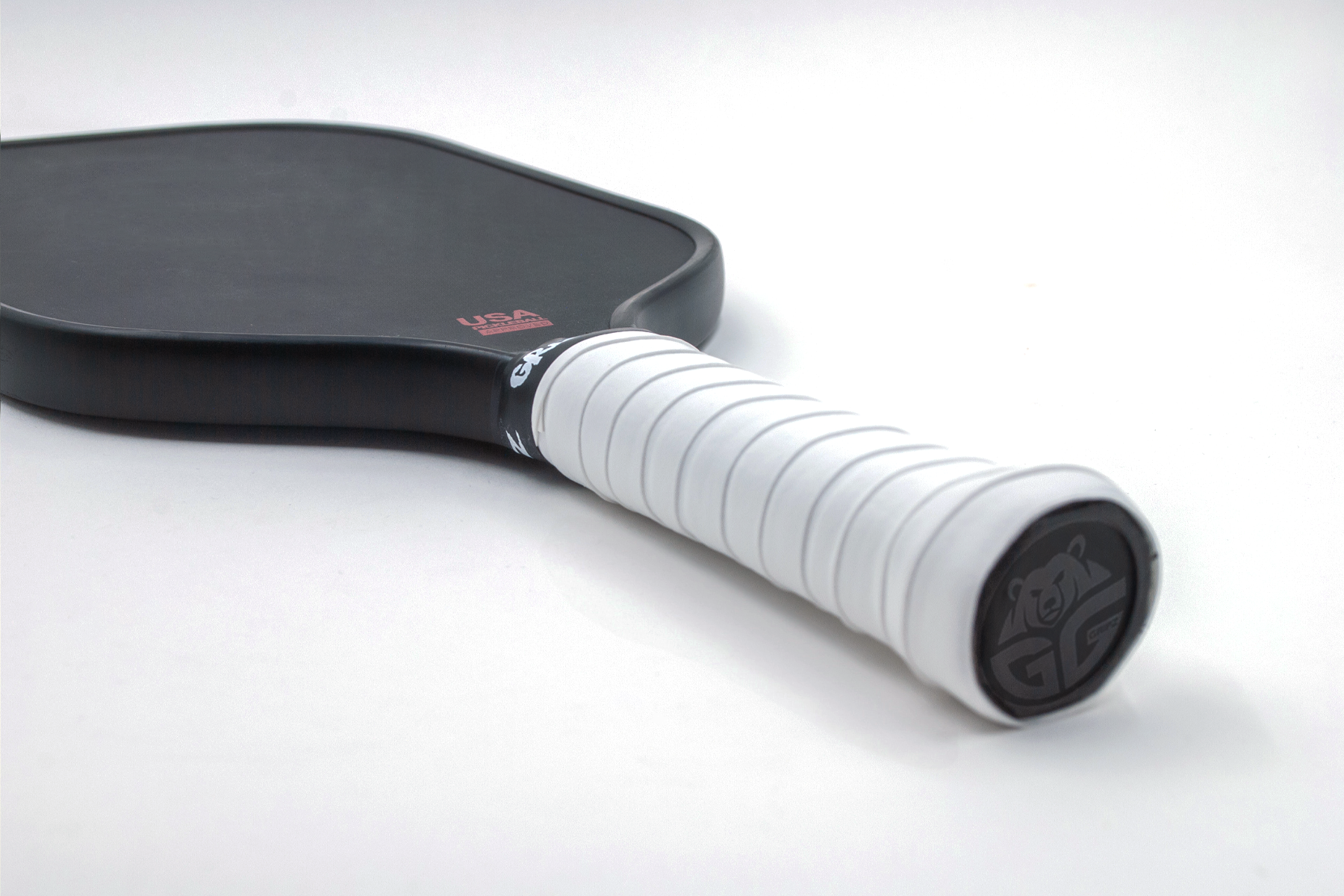 bright white grizzlee gripz overgrip wrapped on a pickleball paddle laying down flat